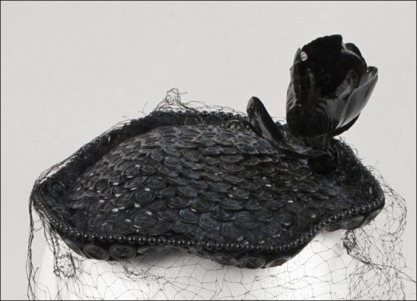 BES-BEN BUTTON HAT.: BES-BEN BUTTON HAT. Entirely covered in black buttons with a single black flower on one side, and trimmed in black beading