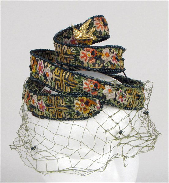 Bes-Ben Spiral Hat: Spiral hat is entirely embroidered with floral chain stitching. Beading throughout hat, and green veil, leads to a hummingbird at the top of the spiral