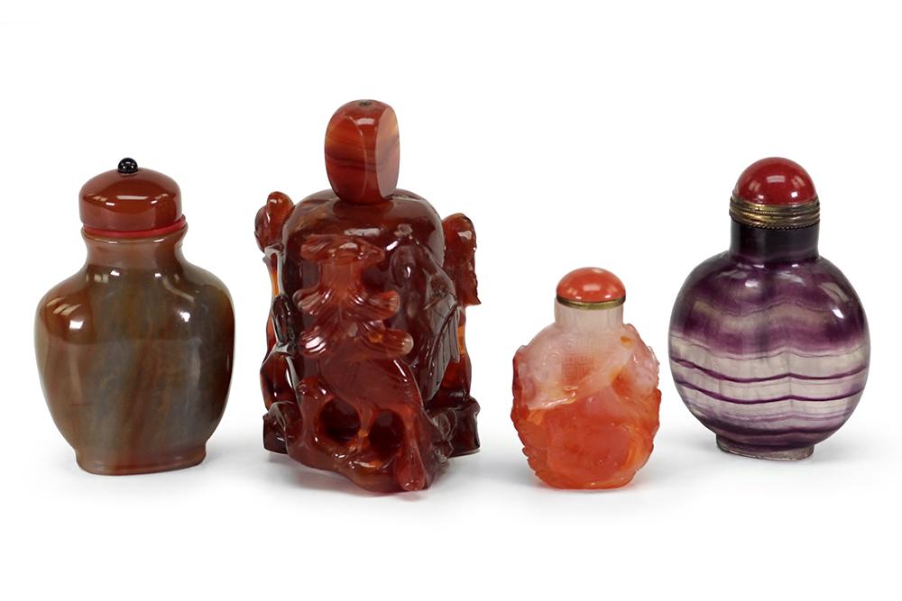 Four Chinese Snuff Bottles.: Four Chinese Snuff Bottles. Comprising a carved carnelian bottle with carnelian stopper, a purple fluorite bottle with semi-precious stone stopper, a carved agate bottle with coral stopper and an agat
