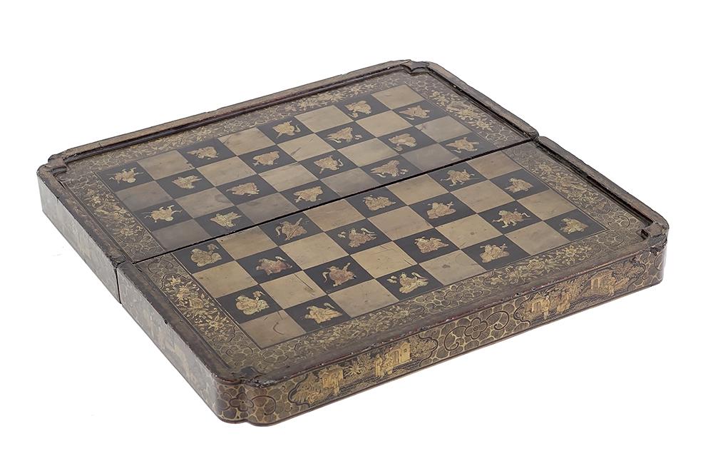A Chinese Lacquered Game Box.: A Chinese Lacquered Game Box. Lacquered game box with a figural decorated chess board on one side and a backgammon board opposite. Without game pieces Closed: 3 1/2" x 19 1/4" x 9 1/2"