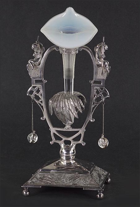 A Meriden Silverplate Vase.: A Meriden Silverplate Vase. Silverplate vase stand depicting winged cherubs fishing on either side of a palm tree form center. Jack in the pulpit form opalescent glass vase is likely a replacement 11 