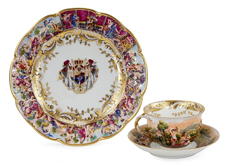 A Capodimonte Armorial Table Service.: A Capodimonte Armorial Table Service. Comprising a set of six plates and six teacups with saucers with hand painted decoration of an armorial crest at center and a Bacchanal procession along the relie