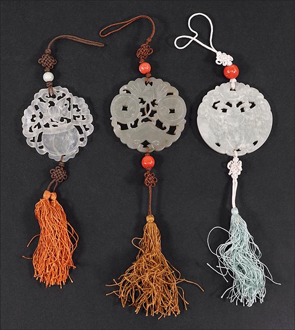 Three Carved Jade Plaques.: Three Carved Jade Plaques. Each plaque with openwork decoration of flowers, a bat and coins. Two plaques are mounted with coral beads and the third a jade bead Largest diameter: 2 3/8"