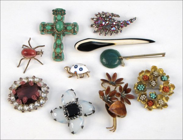 GROUP OF TEN BROOCHES.: GROUP OF TEN BROOCHES. Comprised of one brown enamel floral form brooch, one Hattie Carnegie purple and white rhinestone brooch with glass leaf beads coming into its center, one spider form glass bead