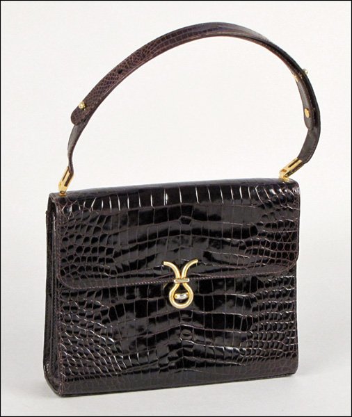 BROWN ALLIGATOR HANDBAG.: BROWN ALLIGATOR HANDBAG. With a gold tone knot closure, two interior zip pockets, and adjustable strap H: 8.5" W: 10.5" D: 3"