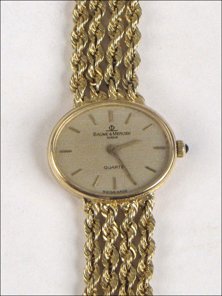 BAUME & MERCIER 14 KARAT YELLOW GOLD LADIES WAT: BAUME & MERCIER 14 KARAT YELLOW GOLD LADIES WATCH. With a four strand gold rope bracelet, and sapphire cabochon capstone. Watch comes with original box Weight of watch: 26 grams