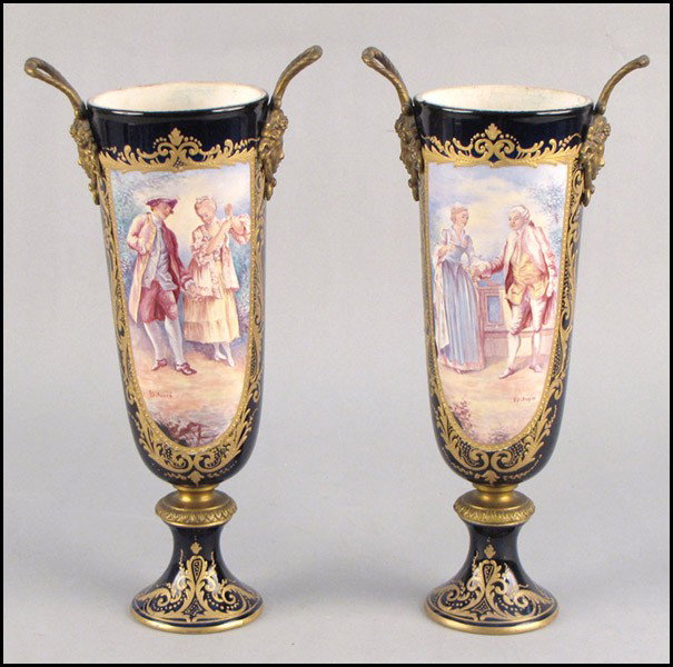PAIR OF SEVRES PORCELAIN URNS.: PAIR OF SEVRES PORCELAIN URNS. With central painted scenes of courting couples surrounded by gilt details and ormolu mounts Height: 13.5"