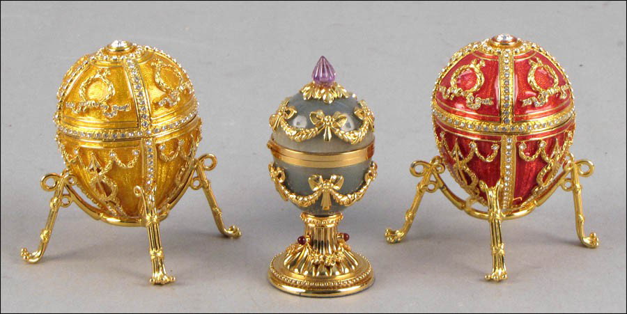 FABERGE RED ENAMEL EGG ON STAND.: FABERGE RED ENAMEL EGG ON STAND. Interior contains an enamel box and egg pendant. Together with a Faberge yellow enamel egg containing an enamel box, and a Faberge egg form box with a clock inside. Al