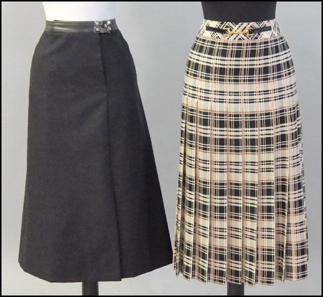 HERMES CHARCOAL GREY WOOL SKIRT.: HERMES CHARCOAL GREY WOOL SKIRT. With a leather waistband, pyramid gromet closure, and front slit. Silk lined. Together with a Celine pleated plaid skirt with horsebit at the waistband Hermes size 46