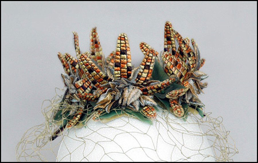 BES-BEN CORN HAT.: BES-BEN CORN HAT. Circa 1962-1963; Crown covered with green plastic leaves dotted with green beads. Clusters of embroided flat corn cobs stand around the perimeter. Green veil