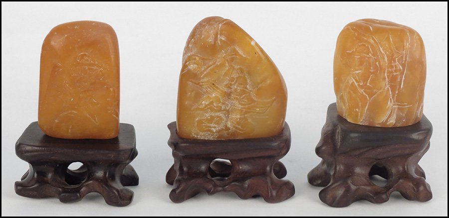 THREE CHINESE ORANGE SOAPSTONE CARVINGS.: THREE CHINESE ORANGE SOAPSTONE CARVINGS. All raised on carved wood bases largest soapstone: 2.2" x 1.75" x 1"