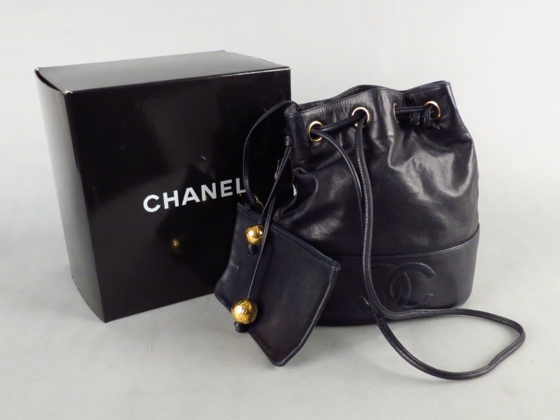 CHANEL LEATHER SHOULDER BAG.: CHANEL LEATHER SHOULDER BAG. With a drawstring closure ending in Chanel gold tone balls, and two shoulder straps. Interior bears a leather zip pouch that is attached by a leather strap. With Chanel au