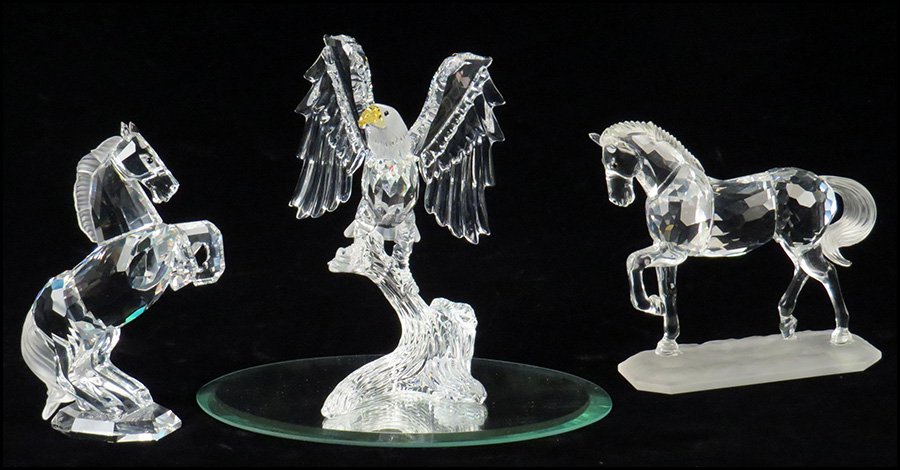 TWO SWAROVSKI CRYSTAL HORSES.: TWO SWAROVSKI CRYSTAL HORSES. Together with Swarovski crystal bald eagle on a mirrored glass base. Includes one horse and eagle with original boxes. Tallest H: 5''