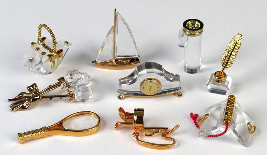 COLLECTION OF SWAROVSKI GOLD PLATED CRYSTAL ITEMS.: COLLECTION OF SWAROVSKI GOLD PLATED CRYSTAL ITEMS. Comprised of a flower basket, a quill and ink, a tennis racquet, a book, a clock, a sailboat, a bouquet of flowers, and a bag of golf clubs. Includes
