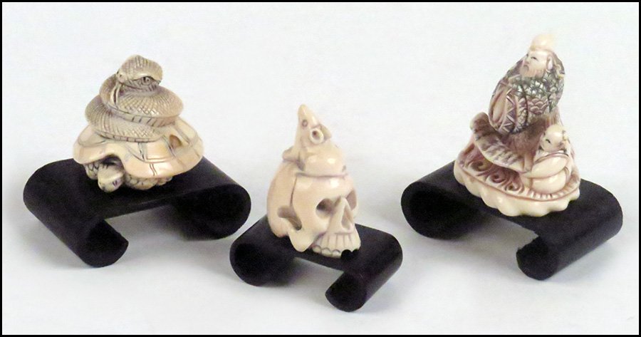 THREE CARVED IVORY NETSUKE.: THREE CARVED IVORY NETSUKE. Comprised of a carved skull with rat perched above, a turtle with a coiled snake above, and a man in a kimono with attendant