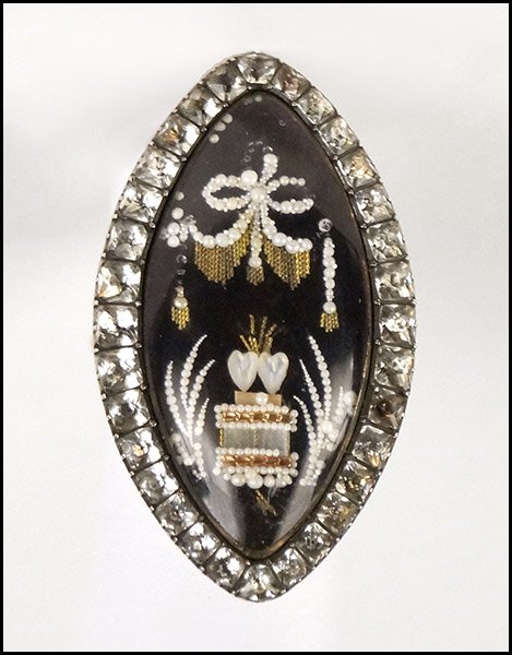 AN ENGLISH 18 KARAT YELLOW GOLD DIORAMA RING.: AN ENGLISH 18 KARAT YELLOW GOLD DIORAMA RING. Depicting two hearts beneath a swag of rope twist and pearls Size: 7 Wt: 10.8 grams