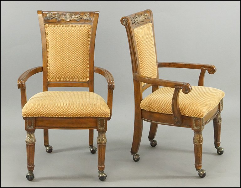 A SET OF FOUR SHERATON STYLE UPHOLSTERED OPEN: A SET OF FOUR SHERATON STYLE UPHOLSTERED OPEN ARMCHAIRS. Bearing a carved foliate motif on the crest, reeded legs, and are raised on casters Each: 38" x 24" x 19"