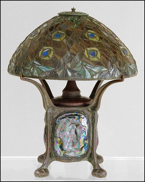 A PATINATED BRONZE TABLE LAMP. Overall: 20" x 16": A PATINATED BRONZE TABLE LAMP. Overall: 20" x 16" $600/$1,000 In the style of Tiffany Studios. Base is comprised of a lantern form with turtleback style iridescent glass panels. Underside of base is n