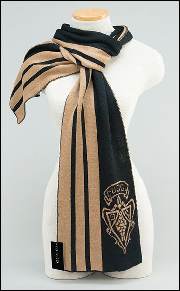 GUCCI WOOL AND CASHMERE BLEND SCARF. $100/$200 Bearing: GUCCI WOOL AND CASHMERE BLEND SCARF. $100/$200 Bearing the signature 'Gucci' logo. Black and camel in color. In the original box