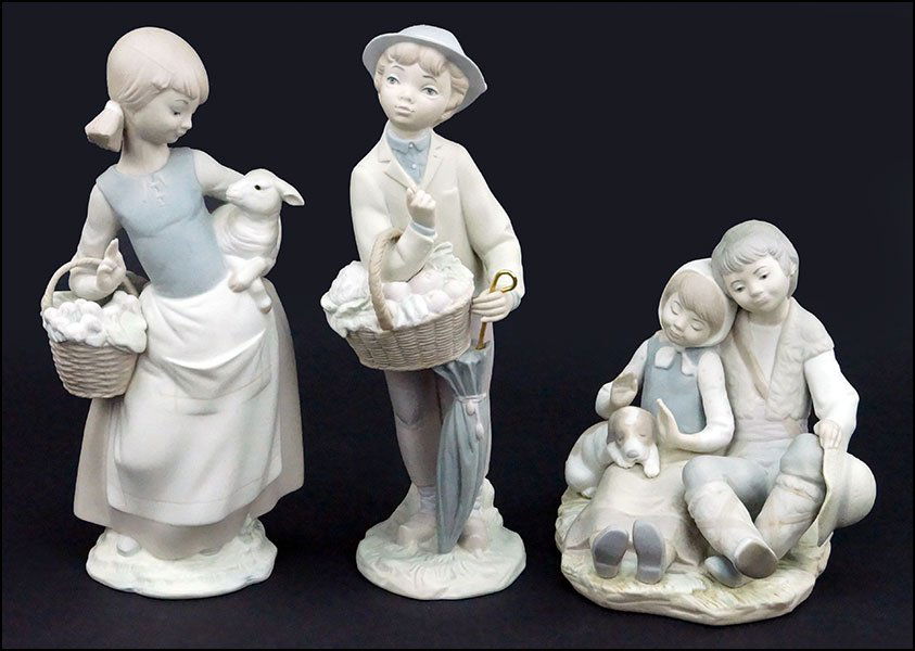 GROUP OF THREE LLADRO BISQUE PORCELAIN FIGURES.: GROUP OF THREE LLADRO BISQUE PORCELAIN FIGURES. Comprised of a figural group of a boy, girl, and dog, a boy carrying a basket of produce and holding an umbrella, a girl carying a sheep and a basket of