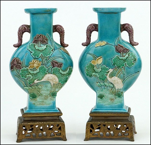 PAIR OF CHINESE PAINTED PORCELAIN VASES.: PAIR OF CHINESE PAINTED PORCELAIN VASES. Of flask form. With elephant trunk form handles on either side. Depicting a heron admist lily pads. Raised and mounted on 2.5'' patinated metal bases Vase H: 8