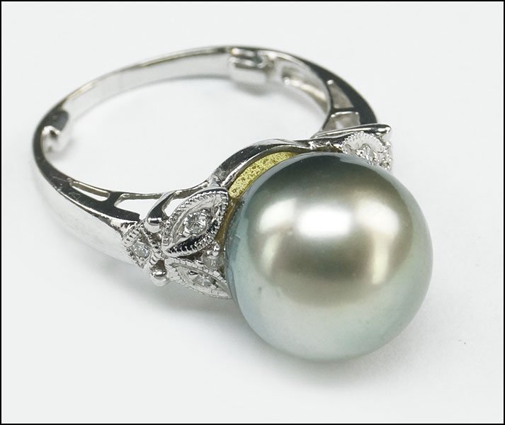 A TAHITIAN PEARL, DIAMOND, AND 18 KARAT WHITE GOLD RING: A TAHITIAN PEARL, DIAMOND, AND 18 KARAT WHITE GOLD RING. Pearl is approximately 12mm. Flanking the pearl are three round diamonds on either side Wt: 6 grams Size: 6
