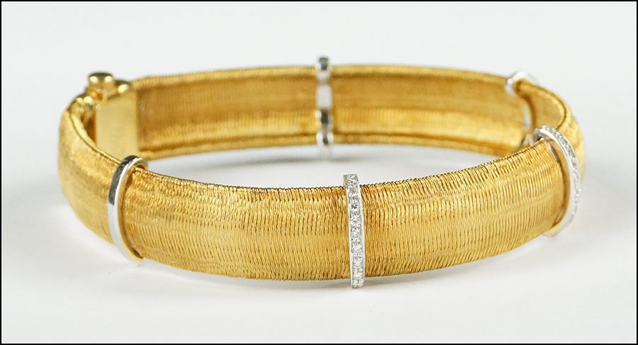 A ROBERTO COIN 18 KARAT YELLOW GOLD AND DIAMOND BRACELE: A ROBERTO COIN 18 KARAT YELLOW GOLD AND DIAMOND BRACELET. Reverse is stamped Roberto Coin and bears an inset ruby on the clasp. Exterior of bracelet contains three bars which are mounted with round di
