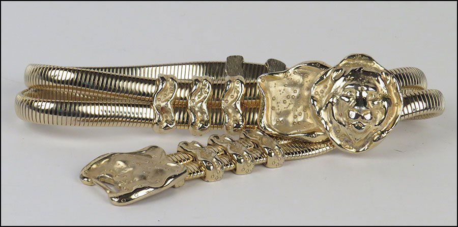 A JUDITH LEIBER GOLDTONE STRETCH BELT.: A JUDITH LEIBER GOLDTONE STRETCH BELT. With a lion form buckle closure L: 28''