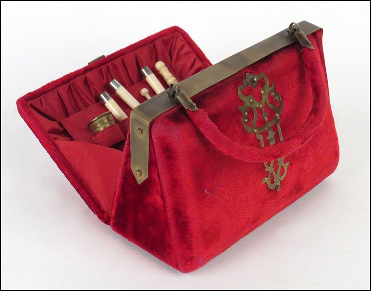 A 19TH CENTURY VICTORIAN RED PLUSH SEWING CADDY.: A 19TH CENTURY VICTORIAN RED PLUSH SEWING CADDY. Of purse form. With tools fitted on the inside. Together with four other handbags, some embroidered, others embellished