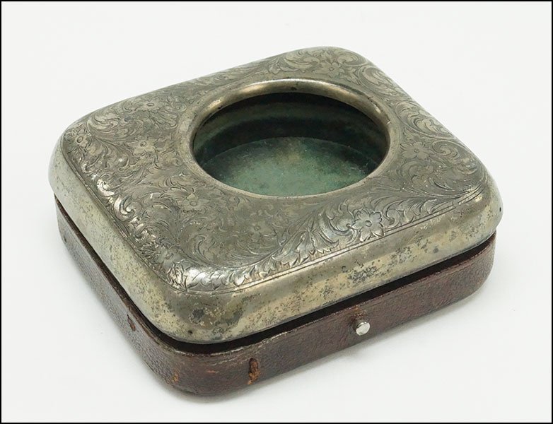 AN AMERICAN STERLING SILVER AND LEATHER POCKET WATCH: AN AMERICAN STERLING SILVER AND LEATHER POCKET WATCH HOLDER. Engraved case cover sits atop a leather case which is lined in green velvet 4" x 4.5" x 1.5"