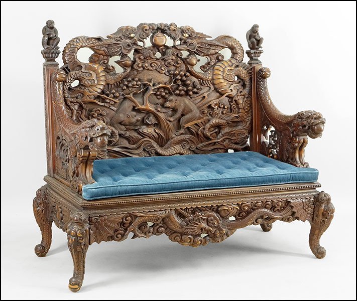 A CHINESE CARVED HARDWOOD SETTEE.: A CHINESE CARVED HARDWOOD SETTEE. Bearing a dragon and foliate motif throughout with a scene depicting monkeys seated in a fruit tree in the back, bone inlaid dragon's eyes at the crest, and carved mo