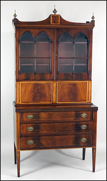 A SHERATON STYLE MAHOGANY SECRETARY BOOKCASE.: A SHERATON STYLE MAHOGANY SECRETARY BOOKCASE. Bearing arched glass panes, inlaid marquetry throughout, a fold down writing surface, and two central doors which open to reveal cubby holes and drawers H
