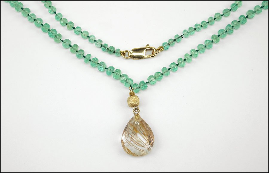A 14 KARAT YELLOW GOLD, FACETED BERYL, AND RUTILATED: A 14 KARAT YELLOW GOLD, FACETED BERYL, AND RUTILATED QUARTZ NECKLACE. Pear shaped rutilated quartz drops from middle of necklace Length: 18"