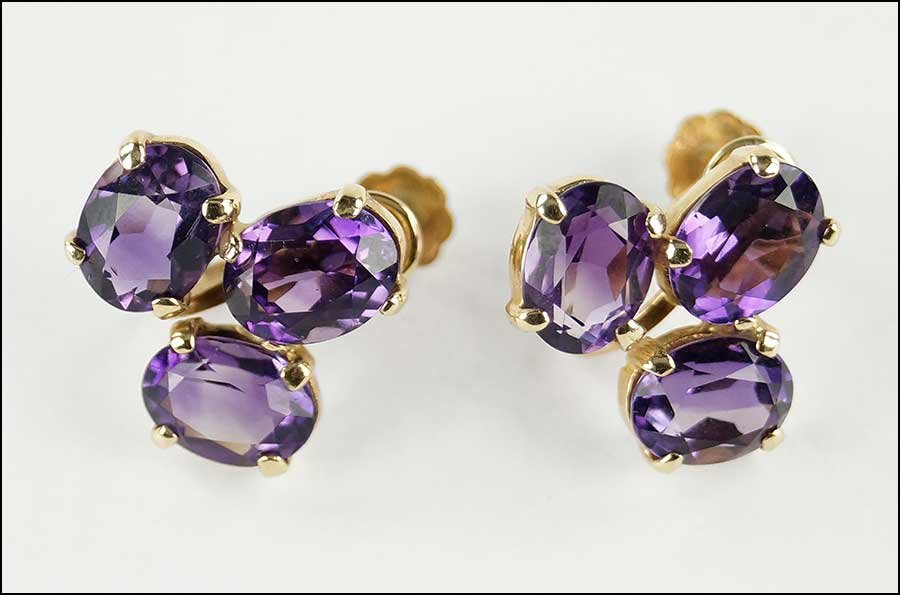 A PAIR OF AMETHYST AND 14 KARAT YELLOW GOLD EARRINGS.: A PAIR OF AMETHYST AND 14 KARAT YELLOW GOLD EARRINGS. Containing three prong set oval cut amethysts on screwback earring Width: .5" Weight: 4.8 grams