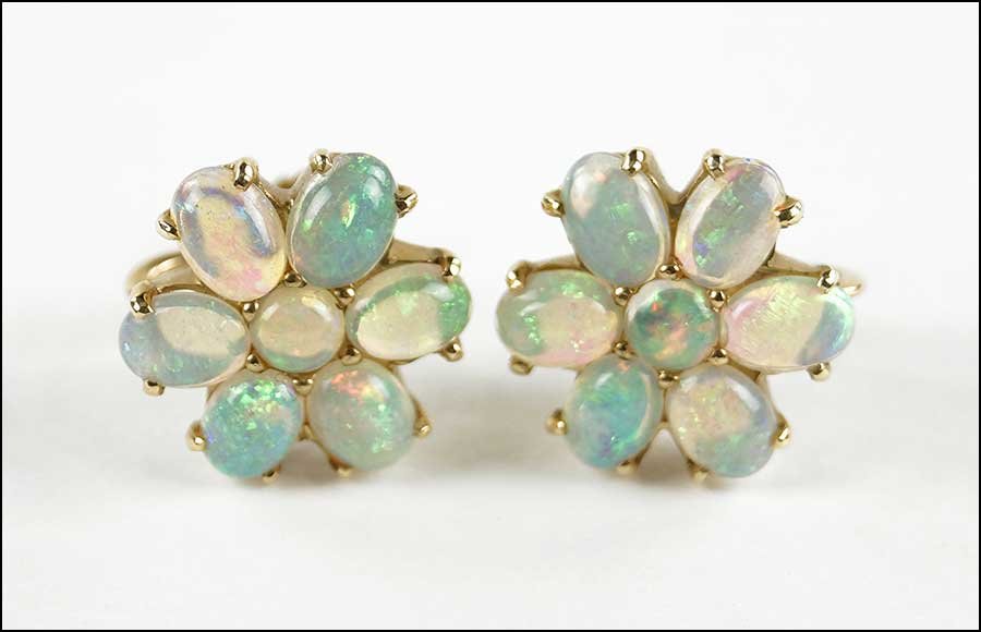 A PAIR OF 14 KARAT YELLOW GOLD AND OPAL EARRINGS.: A PAIR OF 14 KARAT YELLOW GOLD AND OPAL EARRINGS. Each screwback earring contains six oval cabochon opals with one central round cabochon opal Weight: 8.2 grams