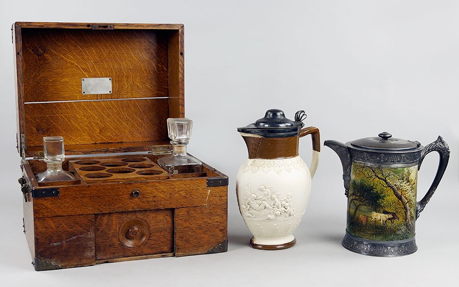 An Adams Porcelain Covered Pitcher.: An Adams Porcelain Covered Pitcher. Partially glazed bisque porcelain pitcher bears a silverplate cover. Together with a painted wood covered pitcher depicting a forest scene, and a tantalus box conta