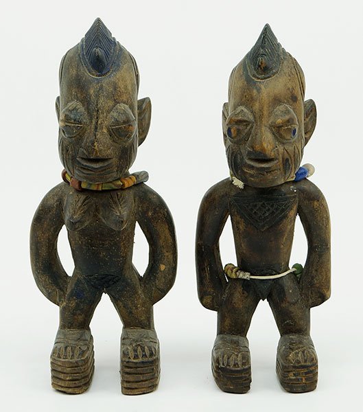 A Pair Of African Carved Wood Ibeji Figures.: A Pair Of African Carved Wood Ibeji Figures. One male, one female. Female bears handmade beaded necklace, male bears handmade beaded necklace and belt Height: 9"