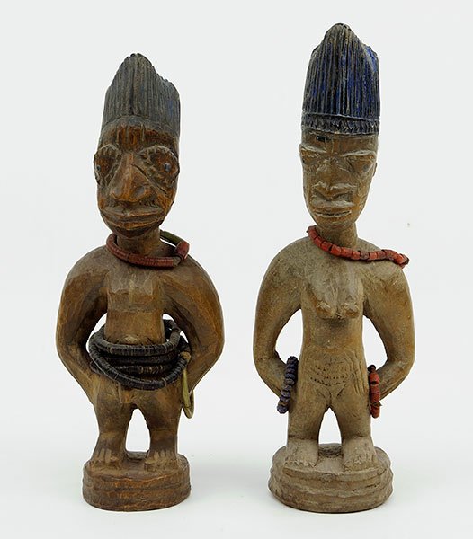 A Pair Of African Carved Wood Ibeji Figures.: A Pair Of African Carved Wood Ibeji Figures. One male, one female. Male figure bears handmade beaded belts and necklace. Female figure bears handmade beaded necklace and bracelets Taller Height: 11"