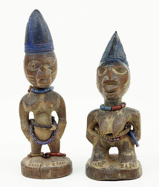 A Pair Of African Carved Wood Ibeji Figures.: A Pair Of African Carved Wood Ibeji Figures. One male, one female. Each bears handmade beaded necklace and belt. Male figure also bears beaded anklets Male Figure Height: 9.5"
