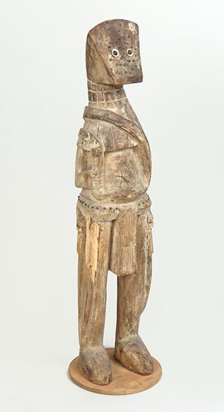 An African Carved Wood Warrior Figure.: An African Carved Wood Warrior Figure. Carved weapons and beaded loin cloth, sitting on a wood base Height: 37" x 8" x 7"
