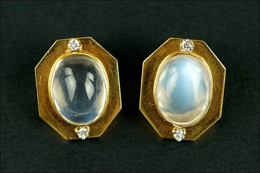 A Pair of Moonstone, Diamond, and 14 Karat Yellow Gold: A Pair of Moonstone, Diamond, and 14 Karat Yellow Gold Ear clips. Each ear clip contains one oval cabochon bezel set moonstone with one prong set round diamond above and below. Clip backing 1" x .75"