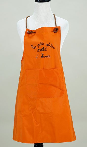 An Hermes Apron.: An Hermes Apron. Polyester jacquard with leather straps. Les Petits Ateliers D'Hermes