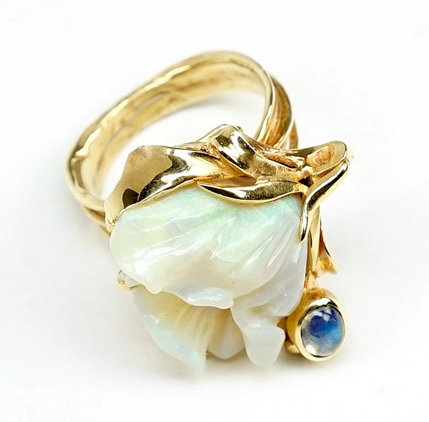 A Carved Opal and 14 Karat Yellow Gold Ring.: A Carved Opal and 14 Karat Yellow Gold Ring. Polished yellow gold mounting in the form of a flower plant with a carved opal flower blossom, next to which is a bezel set oval cabochon moonstone. Revers