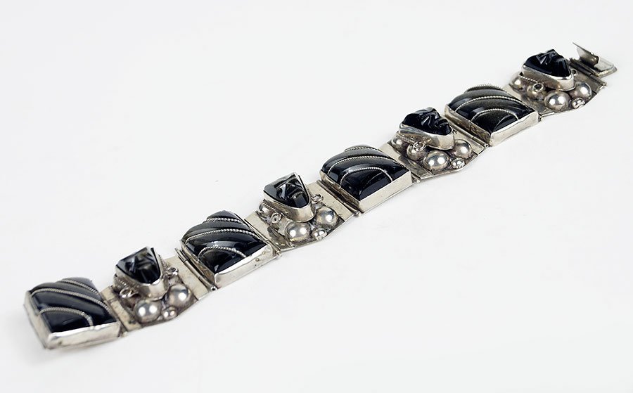 A Mexican Sterling Silver And Obsidian Bracelet.: A Mexican Sterling Silver And Obsidian Bracelet. Comprising square cut obsidian links alternating between face form obsidian links Length: 7.5"