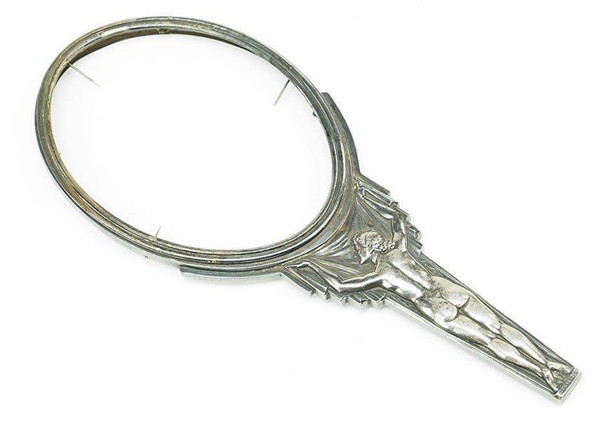 Lucien Bazor (French, 1889-1974) A Hand Mirror.: Lucien Bazor (French, 1889-1974) A Hand Mirror. Silver over bronze hand mirror depicting a nude woman in relief, holding up a drapery panel beneath the oval frame. Signed at base under the feet, "Luci