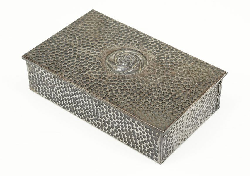 A German Steel Cigar Box.: A German Steel Cigar Box. Faux hammered decoration throughout box is painted within the recessed areas for added depth. Center of lid bears Darmstadt rose in repousse decoration 2.25" x 8.5" x 5.25"