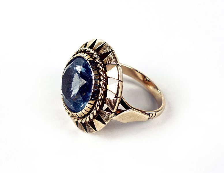 A Synthetic Spinel And 14 Karat Yellow Gold Ring.: A Synthetic Spinel And 14 Karat Yellow Gold Ring. Round faceted synthetic spinel is bezel set within a triangular filigree pattern Size: 6.5 Weight: 9.9 grams