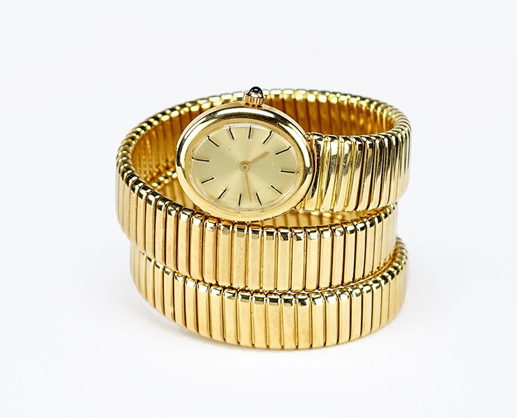 An 18 Karat Yellow Gold Coil Watch.: An 18 Karat Yellow Gold Coil Watch. Coil bracelet forms a snake like body leading into the watch face. Gold colored dial, with a 17 jewel winding movement. Stem contains a cabochon sapphire. Susanin's