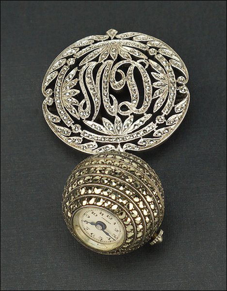 A Bucherer Marcasite Lapel Watch.: A Bucherer Marcasite Lapel Watch. Comprising a brooch / pendant with the stylized initials of "MD" and a pendant round watch. Susanin's will not comment on the working condition of any watch or clock
