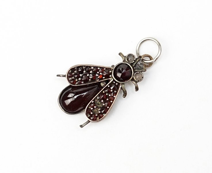 A Garnet Insect Pendant.: A Garnet Insect Pendant. Body contains one pear shaped cabochon garnet. Wings and head contain faceted garnets. Eyes each contain a round cabochon moonstone Length: 21mm
